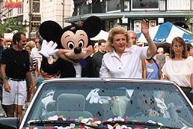Barbara Taylor Bradford and Mickey Mouse wave to the crowd at the end of the parade route from their confetti covered car in Walt Disney World, Orlando, Florida